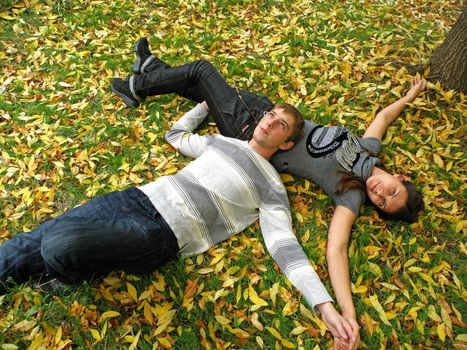 The young pair costs on a footpath in autumn park