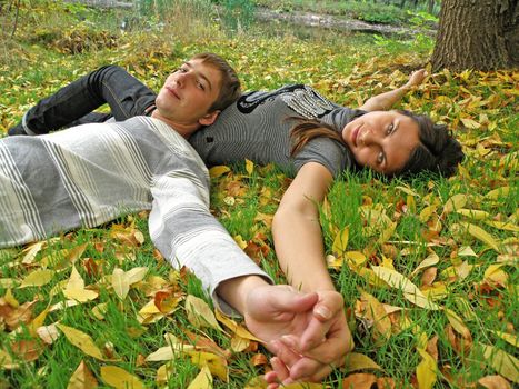 The young pair costs on a footpath in autumn park  