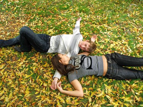 The young pair costs on a footpath in autumn park 