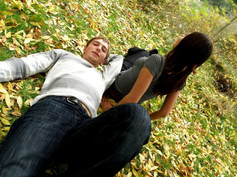 The young pair costs on a footpath in autumn park