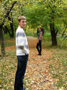 The young pair costs on a footpath in autumn park        