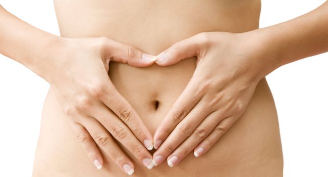 A woman's hands forming a heart symbol on belly 
