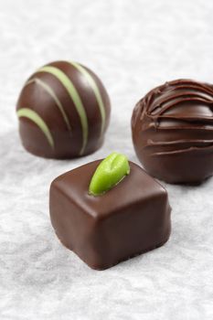 Three chocolate pralines on textured paper.  Very Shallow depth of field, focusing on first truffle.
