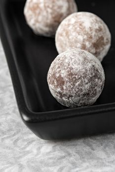 Three chocolate truffles on a black serving tray.  Very Shallow depth of field, focusing on first truffle.
