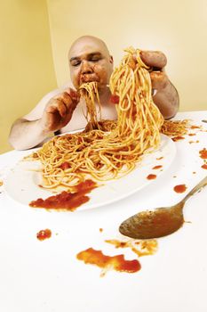 An overweight bald man enjoying a plate of spaghetti.  Shot with fish-eye lens.  Focus is on the face.
