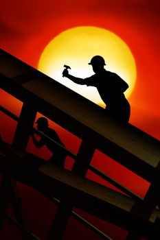 two workers on a roof top with sunset