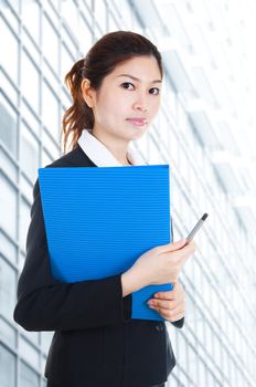 Young Business Women holding file standing in front building block.