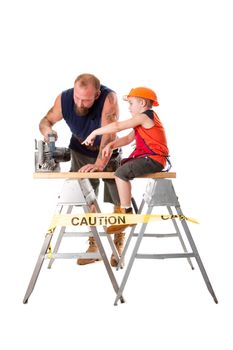 Cute son is helping dad cutting a wooden plank with a heavy duty circle saw as he is pointing out how to do it, isolated. Boy sitting on wooden board and pointing at circle saw that his father is using.