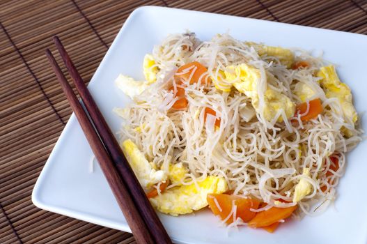 Asian fried rice vermicelli with eggs and carrot. Serve with chopsticks.