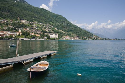 View of Gravedona, on the Lake Como, surrounded  by the Alps, at the North of Italy.Wooden boat and jetty on the front.