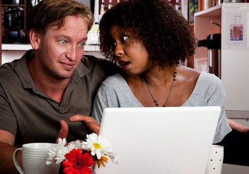 Caucasian man and African American woman in coffee house with laptop computer