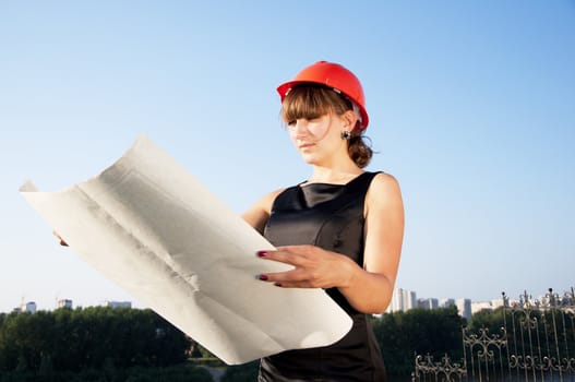 Business woman considers construction plans, blue sky background