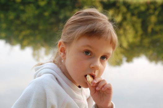 little 5 year old girl eating on the riverbank
