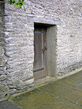 Old wooden door, set against a thick stone wall on a path near Buckfast Abbey in Devon, England