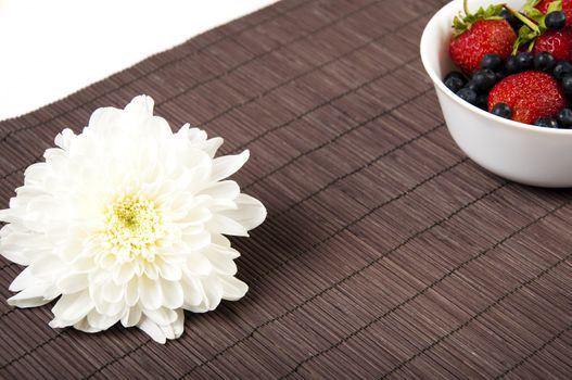 light Breakfast: flower and Berries on a table on a bamboo background