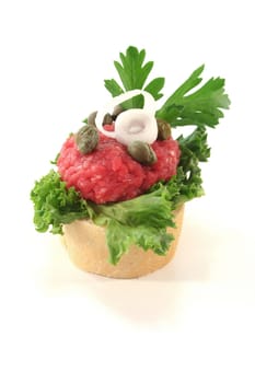 Canape with lettuce, Tartare; capers; onions and parsley on a white background