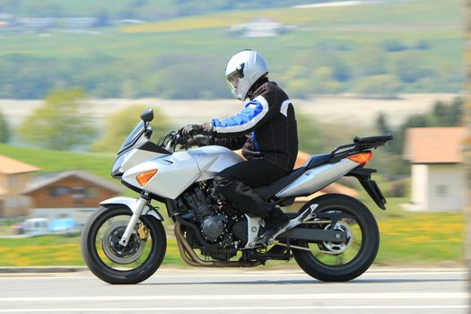 Biker wearing black clothes and driving a big motobike in the countryside