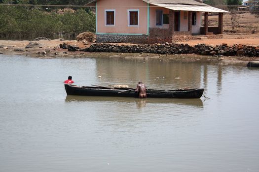 A naked Indian saint climbing up his boat after a holy bath in the river, near his hermitage.