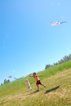 two kids flying kites on the summer meadow