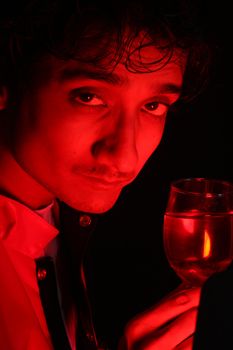 A portrait of a drunk Indian man holding a glass of wine, in red party lights.