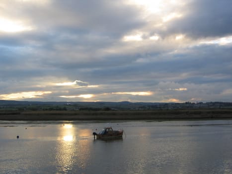 Sunset Through Clouds Over English River with Small Motor Boat