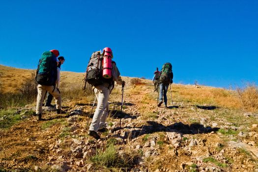 Group of hikers climbing up the rocky mountain