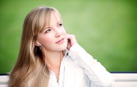 Young woman listening to the music outdoors and dreaming