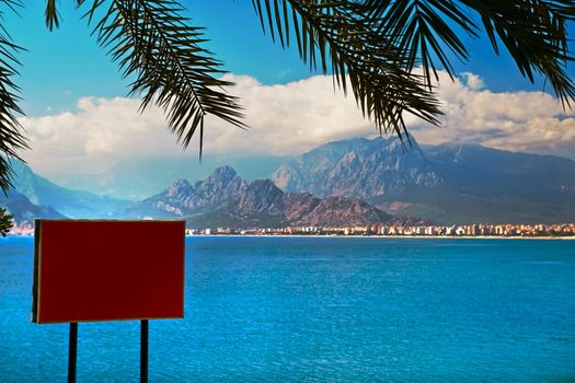 Bright red information board at sea shore with  mountains in background