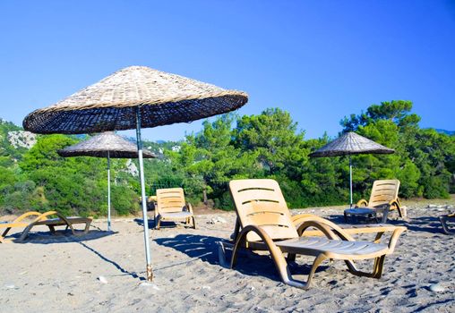 Yellow tropic parasols and beach chairs on shingle beach in sunny weather