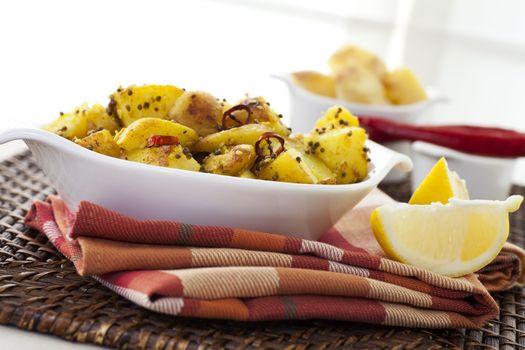 Spicy Potatoes with mustard seeds, sesame seeds, chili peppers and other spices, served with a slice of lemon.