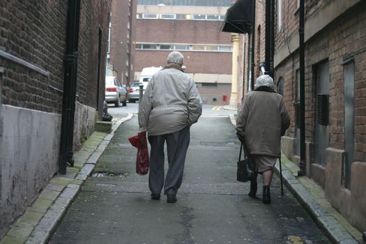 Old Couple Climbing a Hill After Shopping