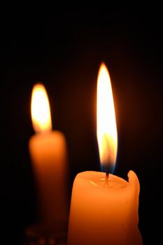 Two candle flames shining in the darkness
