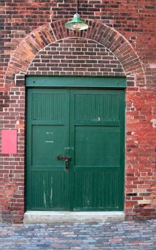 The green door of an old red brick warehouse.