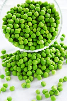 young fresh green spring peas scattered from glass bowl