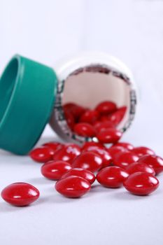 A spilled bottle of red pills of prescribed medicines.