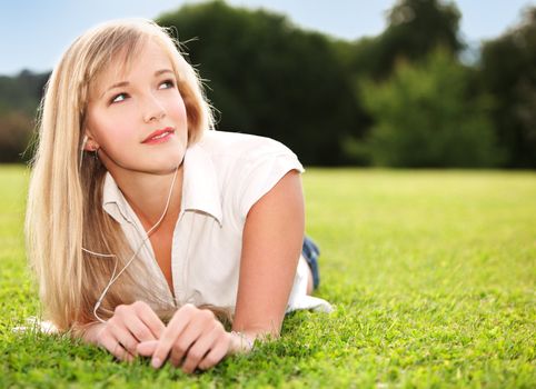 Image of young attractive woman lying on the grass and dreaming about her future