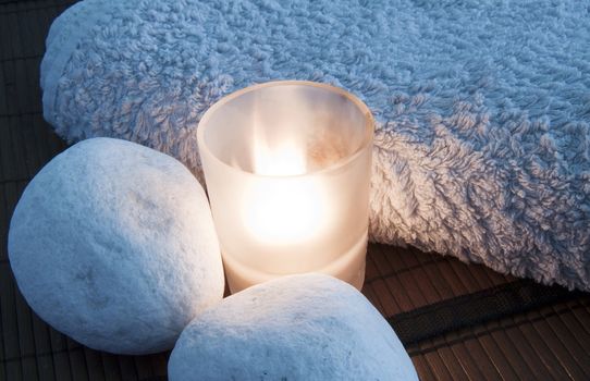 Closeup of a candle, two stones and towel