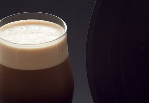 Close up of a glass of irish stout with a vinyl record