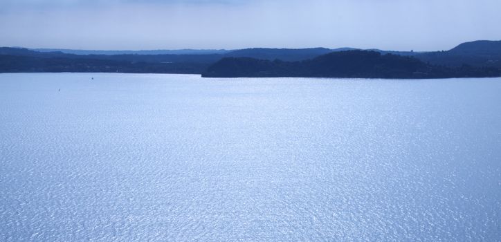 Blue landscape of lake with dark mountains in the background