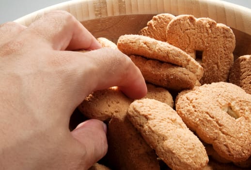 Male hand taking biscuits from a wooden bowl