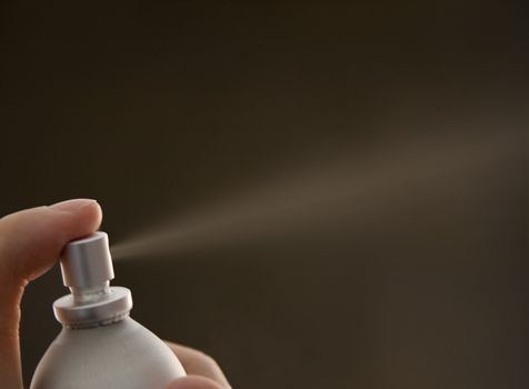 Hand clicking a can of spray perfume 