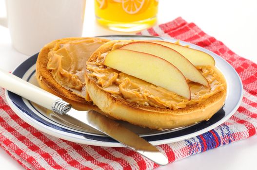 Toasted bagel with peanut butter and apple slices.