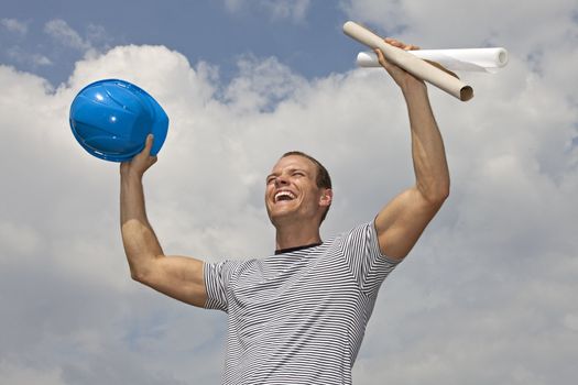 smiling young architect holding a hard hat and blueprints