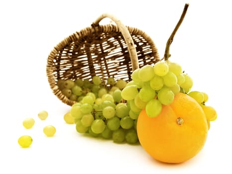 green grape and orange scattered from basket against the white background