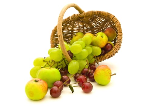 scattered grape cherry and apples in hand-made basket against white background  