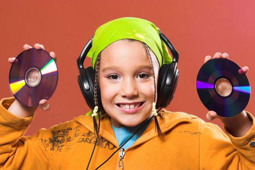 little pretty child listening music in headphones and holding two CD 