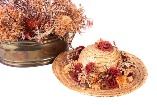 Straw hat with autumn colours and a metal vase with an autumn dry bouquet.