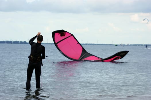 Kite surfer is pulling the ropes to make his sail fly