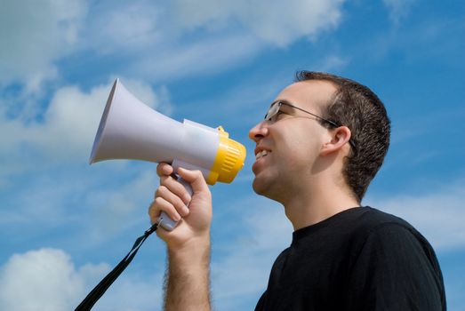 A low angle view of a man talking into a megaphone with the sky behind him