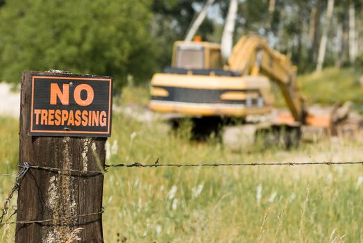 No trespassing at this work site featuring the sign and an excavator